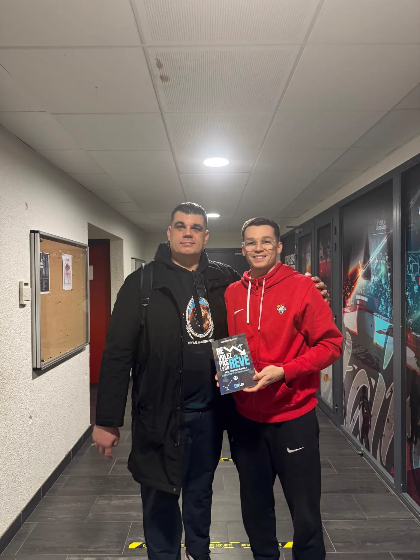 Jean Pierre Ciesielski with a young player holding his book in a team hallway