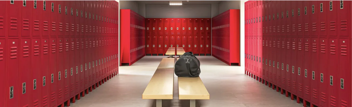 Red locker room with a sports bag resting on an empty bench