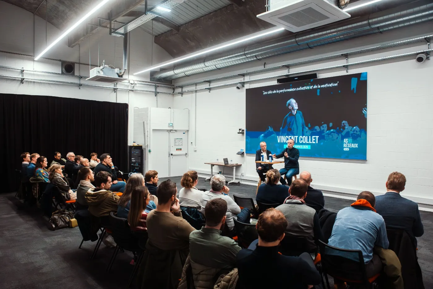 Audience at a speaking event with two panelists